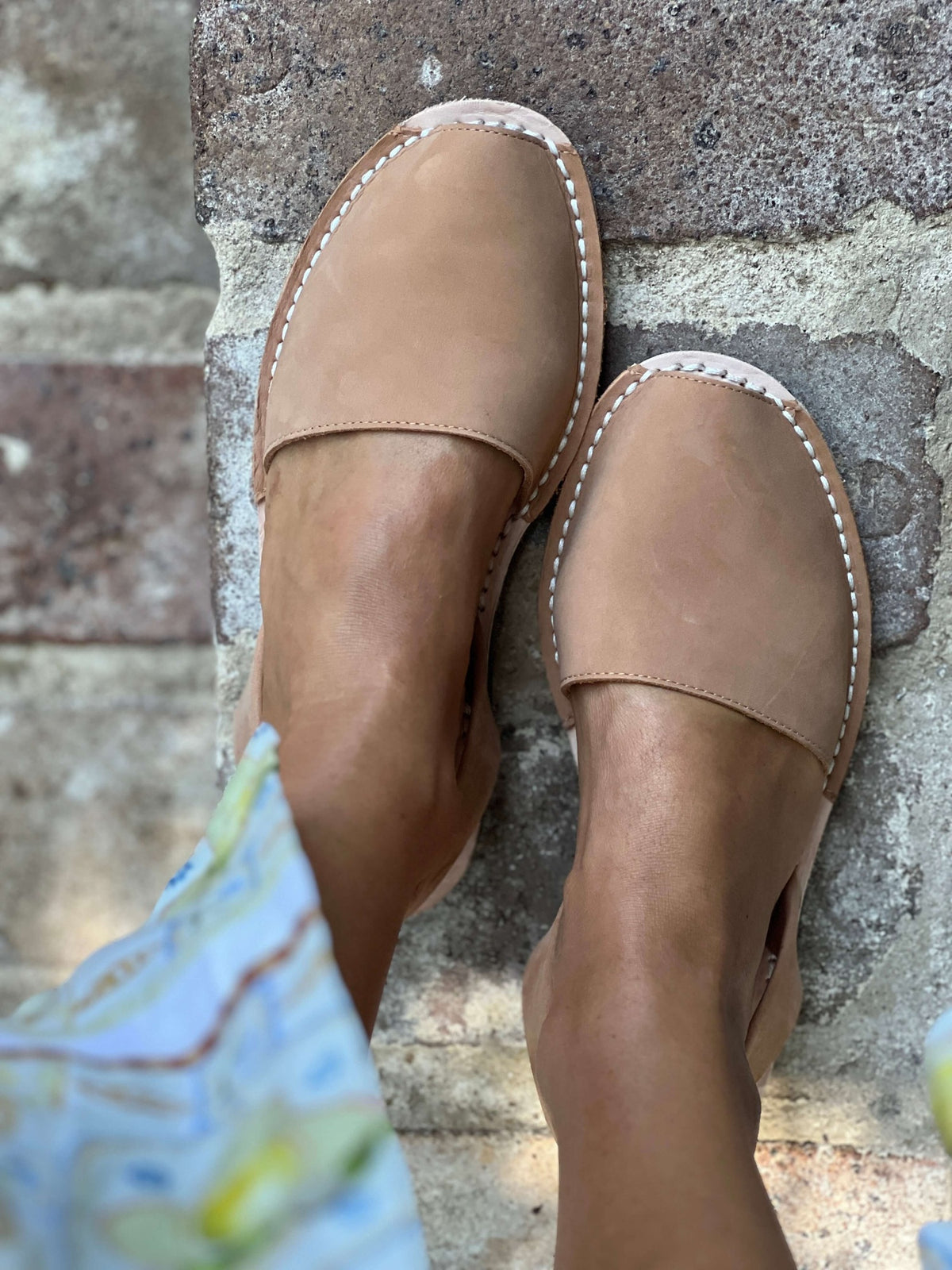 Pair of tan nubuck leather sandals on a stone surface