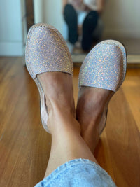 Silver glittery shoes worn indoors on a wooden floor.