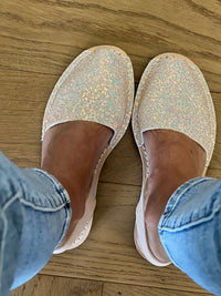 Pair of glittery shoes on a wooden floor with denim jeans.