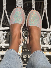 Tesalia flat shoes worn with light blue jeans on a white chair.