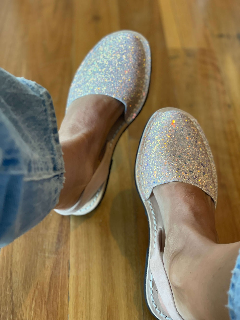 Silver glittery shoes worn on a wooden floor