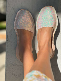 Glittery flat shoes worn by a person standing on a concrete surface.